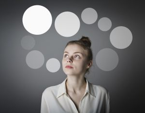 Girl in white having an idea with gray bubbles over her head. Young slim woman.